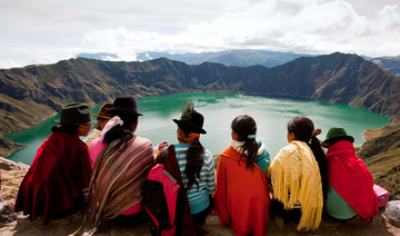 kichwa girls (descendants of the Incas) sit in front of the Ecuadorian lake Quilotoa, formed within a volcano crater about 800 years ago.