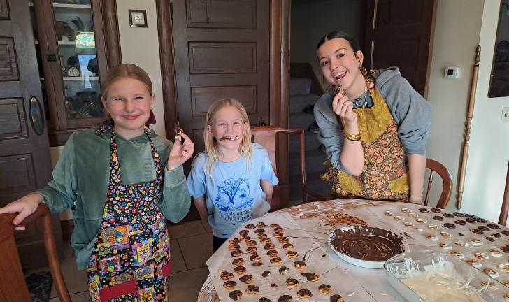 student making chocolate pretzels with host siblings